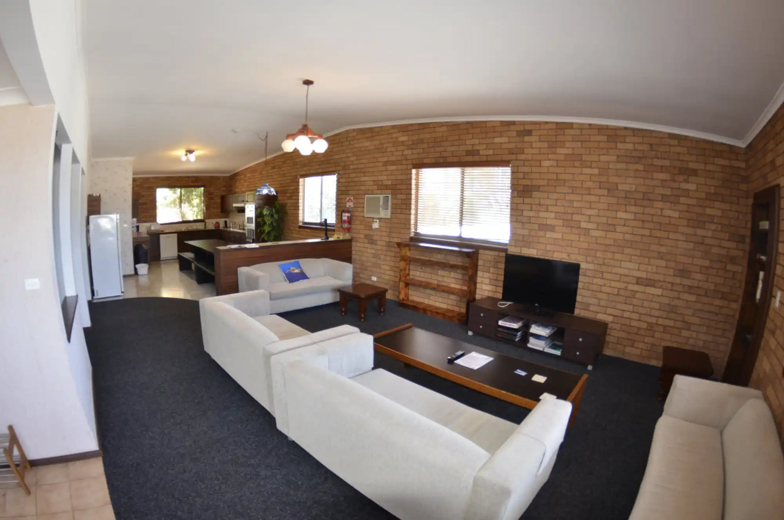 Modern open-concept living room with white sofas and exposed brick walls.