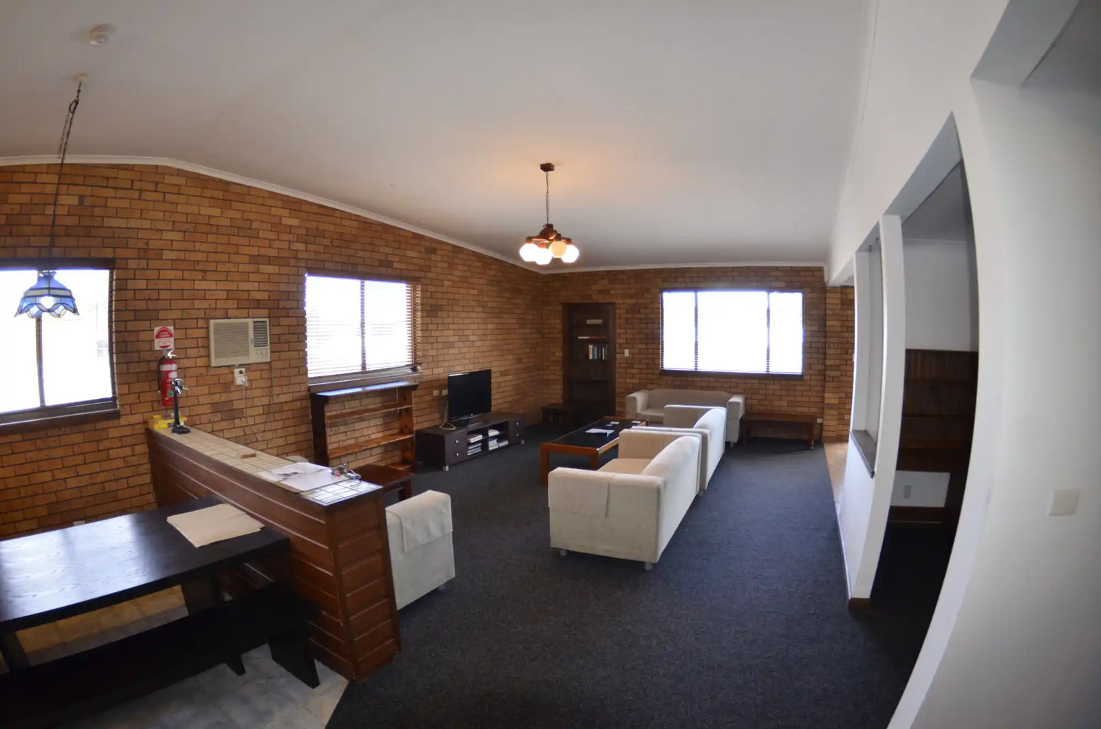 A living room with wood-paneled walls and white furniture.