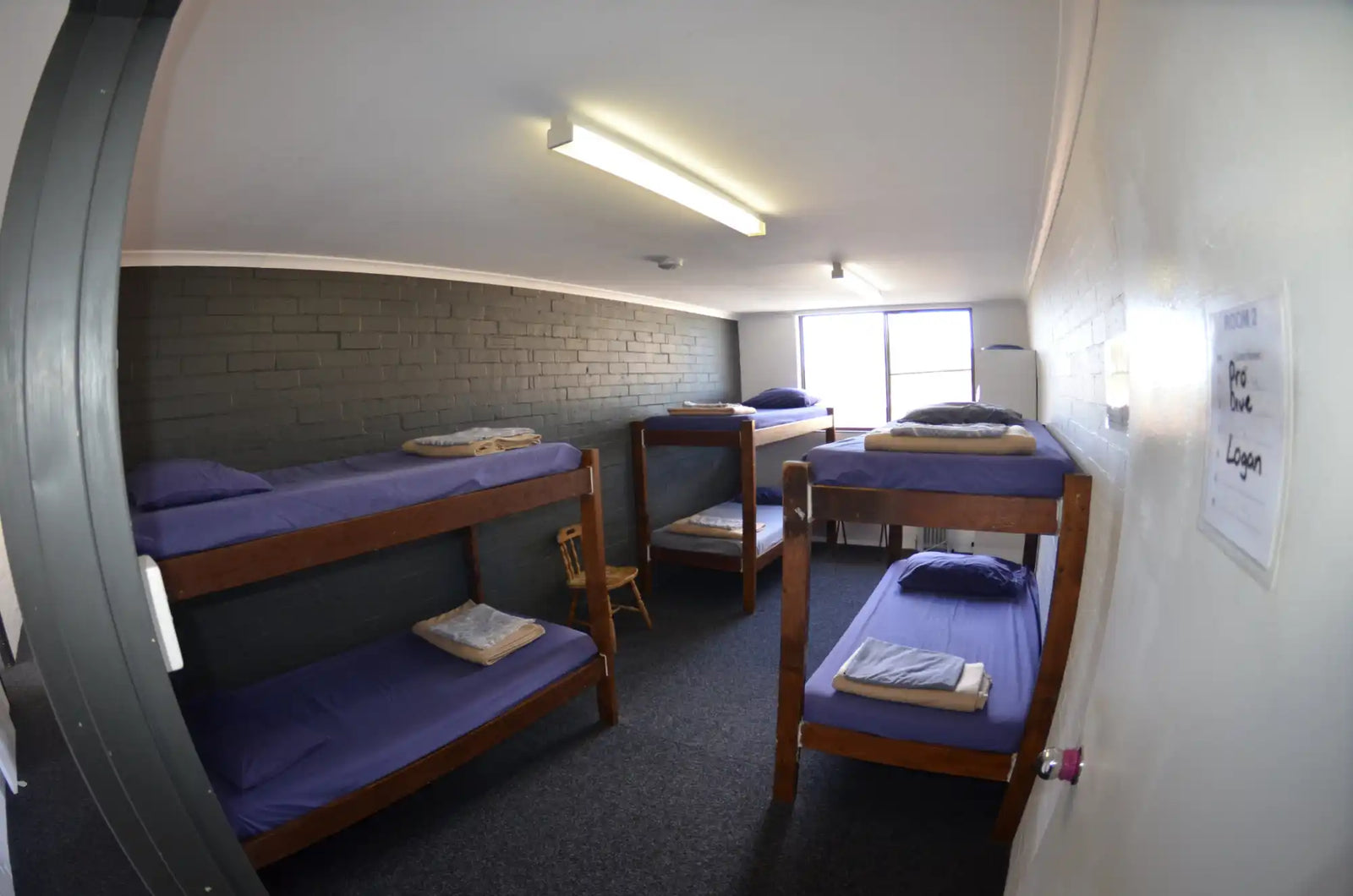 Wooden bunk beds with purple mattresses arranged in a dormitory-style setup.