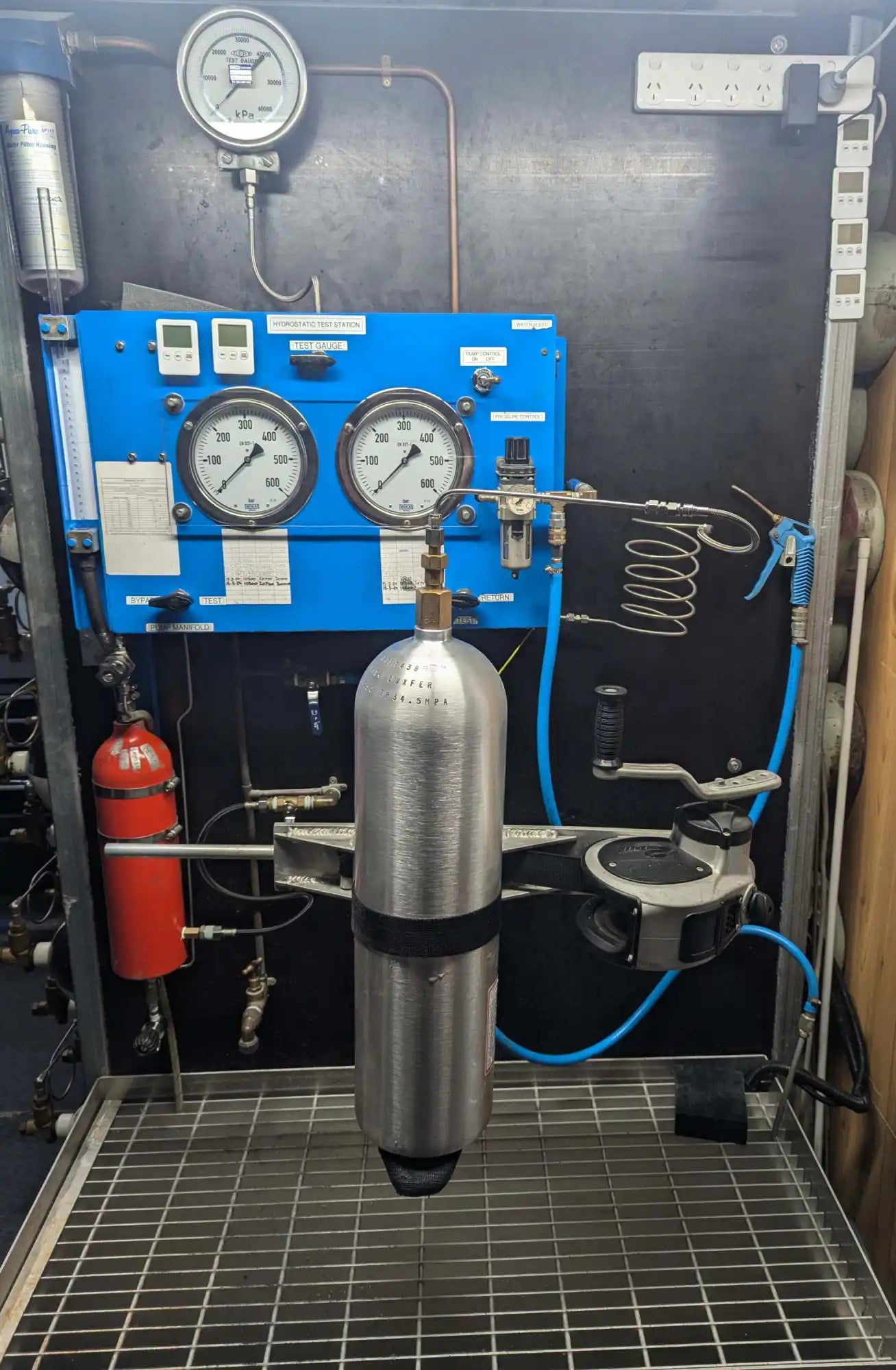 Industrial pressure testing system with gauges, tanks, and pneumatic components mounted on a metal frame.