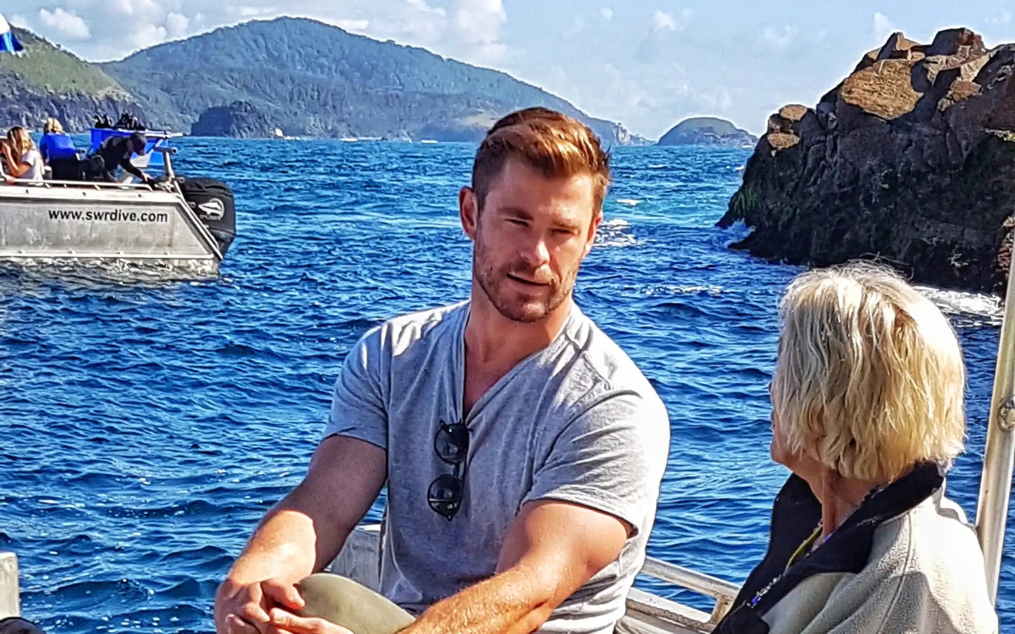 A person wearing a grey t-shirt sitting on a boat.