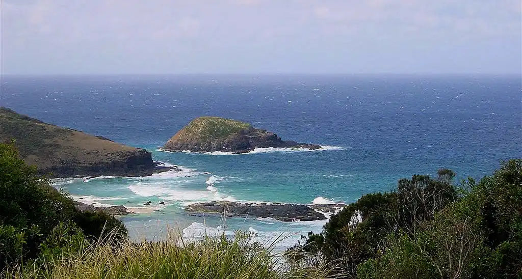 Rocky coastal island surrounded by turquoise ocean waves.