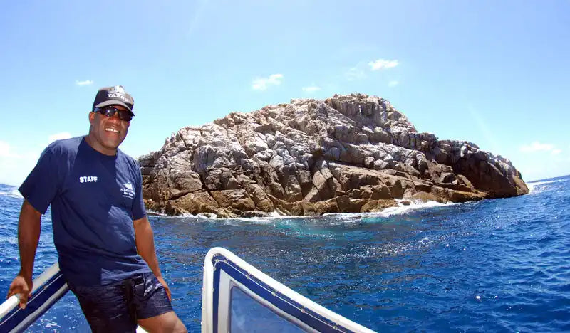 Rocky island formation rising from bright blue ocean waters.